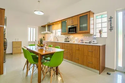 a kitchen with a wooden table and green chairs at Mantarini House in Áyios Andónios
