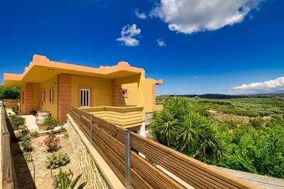 a small yellow house with a wooden fence at Mantarini House in Áyios Andónios