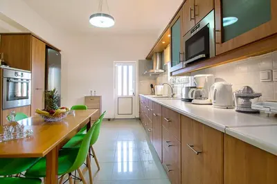 a large kitchen with a table and green chairs at Mantarini House in Áyios Andónios