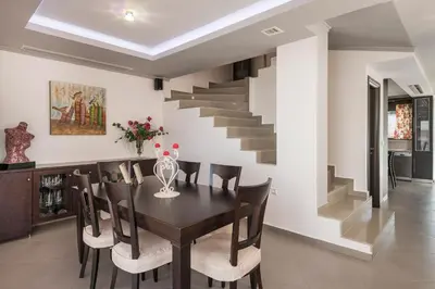 a dining room with a table and chairs and a staircase at Villa Antoni in Galatás
