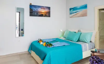 a white room with a bed with blue sheets at Apolafsi Apartments 2 New with kitchen in Chania Town