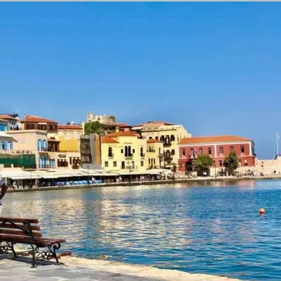 a bench sitting next to a body of water with buildings at Apolafsi Apartments 2 New with kitchen in Chania Town