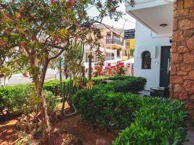 a garden in front of a house with trees and bushes at Ostria Apartments Kalives in Kalyves