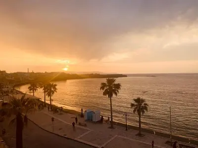 a view of a beach with palm trees and the sunset at Zonapartments B sea view- city center in Chania Town
