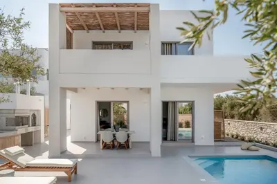 a white house with a pool and a dining room at Anthos Villas - Chania in Tavronitis