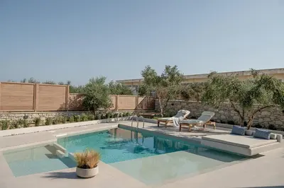 a swimming pool with two chairs and a table next to it at Anthos Villas - Chania in Tavronitis