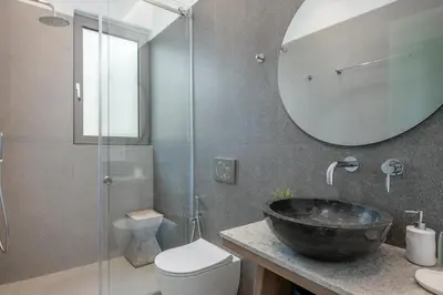 a bathroom with a sink and a toilet and a mirror at Anthos Villas - Chania in Tavronitis