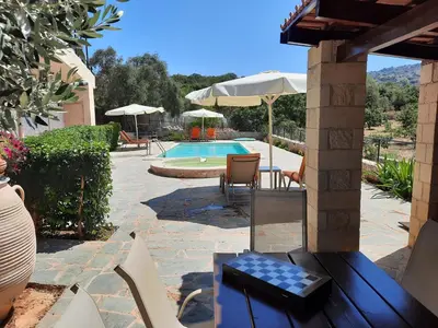 a patio with a table and chairs and a pool at Villa Maragoudi in Arménoi