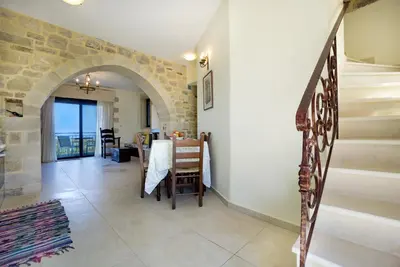 a hallway with a staircase and a dining room with a table at Casa Rustica in Xirokámbion