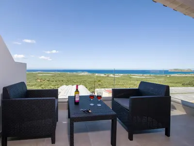 a patio with two chairs and a table with wine glasses at Petras Resort in Falasarna