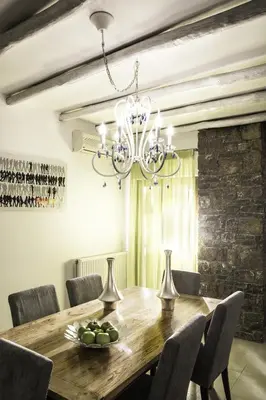 a dining room with a wooden table and a chandelier at Villa Kalithea in Pemónia