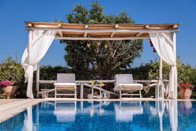 a gazebo over a swimming pool with two chairs at Villa Kalithea in Pemónia