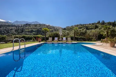 a blue swimming pool with a mountain in the background at Villa Kalithea in Pemónia