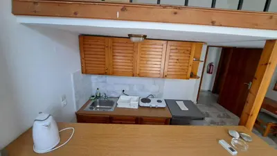a small kitchen with a sink and wooden cabinets at Artemis Studios in Agia Roumeli