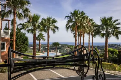 a park bench with palm trees in the background at Athina Luxury Villas in Xamoudhokhórion