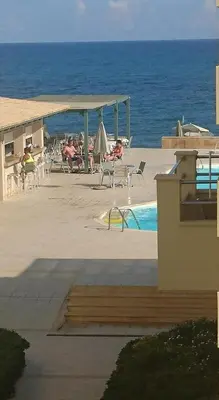 a swimming pool with people sitting in chairs near the ocean at Lissos Beach in Plataniás