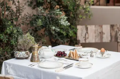a table with a white table cloth with plates and cups at La Maison Ottomane in Chania Town