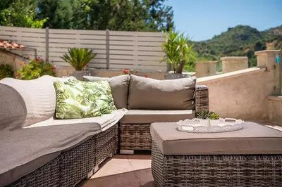 a wicker couch and ottoman sitting on a patio at Verekinthos Villas - Pool, Hot Tub, BBQ, Kids Playground, Stunning Mountain Views in Gerolakkos