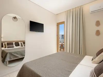 a hotel room with a bed and a mirror at Esperides Beach Hotel Apartments in Stalos