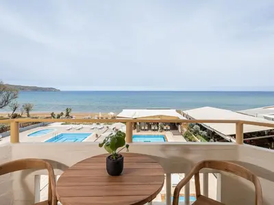 a table on a balcony with a view of the ocean at Esperides Beach Hotel Apartments in Stalos