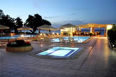 a swimming pool with chairs and tables and a restaurant at Esperides Beach Hotel Apartments in Stalos