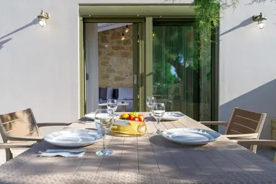 a wooden table with glasses and a bowl of fruit on it at Zefyros Apartments and House in Kissamos