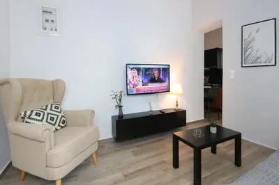 a living room with a chair and a tv on a wall at Comfy Apartment in Chania Town