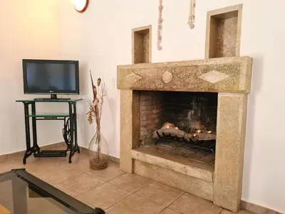 a stone fireplace in a living room with a tv at Basilikos traditional house, 10' from Falasarna in Kissamos