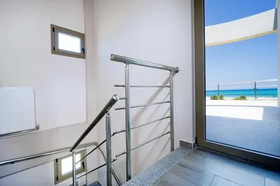 a staircase with a glass door with a view of the beach at Beach Villas in Chania Town