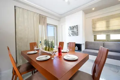 a dining room with a wooden table and chairs at Beach Villas in Chania Town