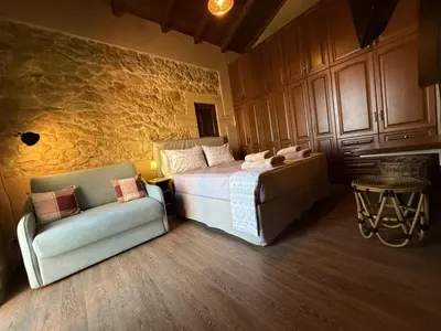 a bedroom with a bed and a couch and a chair at ARIALKiS - ΑΡΙΑΛΚίΣ in Plataniás