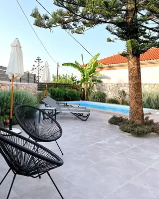 a patio with two chairs and a tree and a pool at Villa Christini a luxury villa with amazing views in Tzitzifés