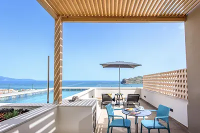 a balcony with a table and chairs and a view of the ocean at Caldera Village in Agia Marina Nea Kydonias