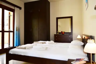 a bedroom with a bed with white sheets and a mirror at Villa Spilia Homeleader in Spiliá