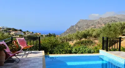 a patio with two chairs and a swimming pool at Villa Ravdoucha Homeleader in Ravdhoúkha