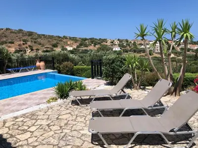 a group of chairs sitting next to a swimming pool at Villa Ravdoucha Homeleader in Ravdhoúkha