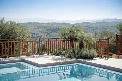 a swimming pool with a fence and mountains in the background at Villa Hibiscus in Spiliá