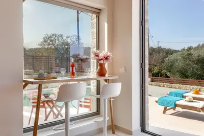 a dining room with a table and a large window at Canna Villa in Vamos