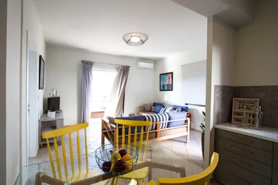 a living room with a table and yellow chairs at Mike's apartment I Luxury above the sea in Kissamos