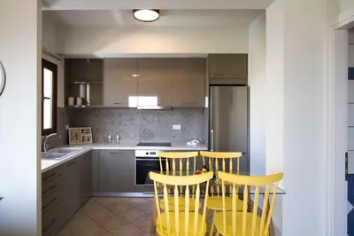 a kitchen with yellow chairs and a table in it at Mike's apartment I Luxury above the sea in Kissamos