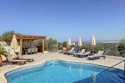 a swimming pool with chaise lounges and umbrellas at Pano Stalos Villas in Stalos