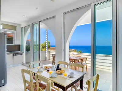 a dining room with a table and a view of the ocean at Villa Anemos by Estia in Kalathas