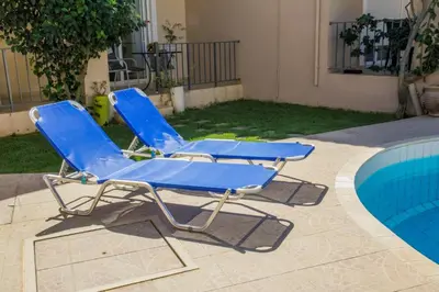 two blue lounge chairs next to a swimming pool at Villa Nopigia Homeleader in Nopíyia