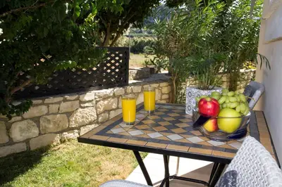 a table with a bowl of fruit and two glasses of orange juice at Villa Nopigia Homeleader in Nopíyia