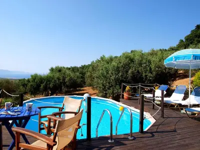 a pool with chairs and a table and an umbrella at Villa Papoura Homeleader in Delimanolianá