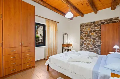 a bedroom with a bed and a stone wall at Kambos Horizon & Paradise Villas in Kissamos