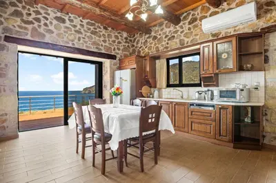 a kitchen with a table with chairs and a view of the ocean at Kambos Horizon & Paradise Villas in Kissamos