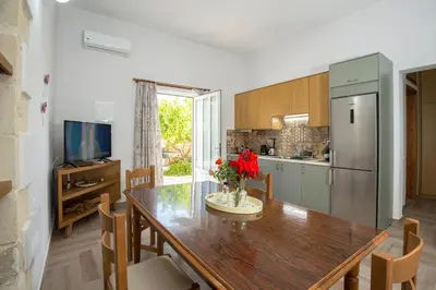 a kitchen with a dining room table and a refrigerator at Eliana's Stone House in Benoudhianá