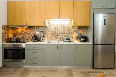 a kitchen with wooden cabinets and a stainless steel refrigerator at Eliana's Stone House in Benoudhianá