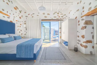 a bedroom with a blue bed and a large window at Veranta Luxury Suite in Khóra Sfakíon